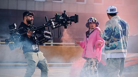 TRINITY operator Omer Belli filming two actors on a rooftop with smoke around them