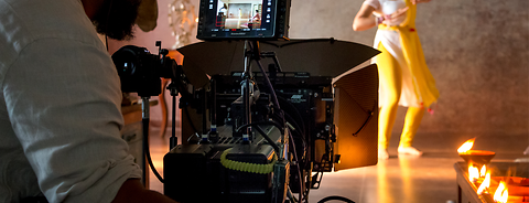 Man filming a dancing woman with a camera that has an ARRI matte box mounted on it