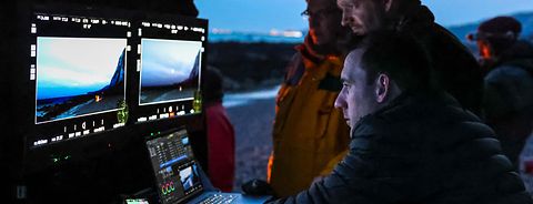 People looking at two screens of the DTI cart on a low-lit movie set