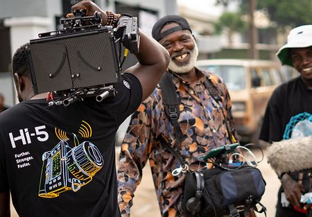 Three men carrying equpment (camera & sound)