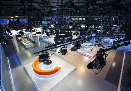 Glance from top of a studio's lighting-installation down to the stage showing the studio and numerous broadcasting equipment.