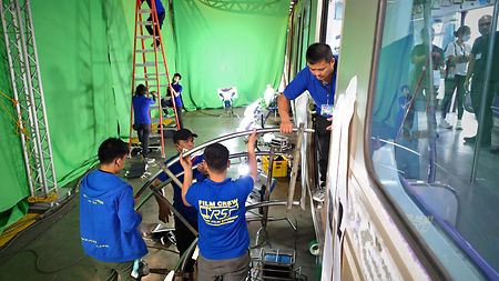 Crew members installing and lighting the green screen for VFX sequences