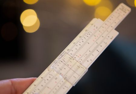 Image of a hand holding a slide rule